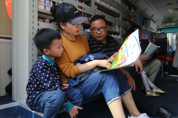 4月21日,在恩施州公共图书馆阅读推广联盟巡展现场,读者在“流动图书车”上阅读图书
