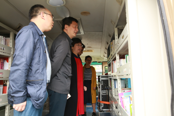 4月24日,在宣恩活动现场,领导在流动图书车上参观